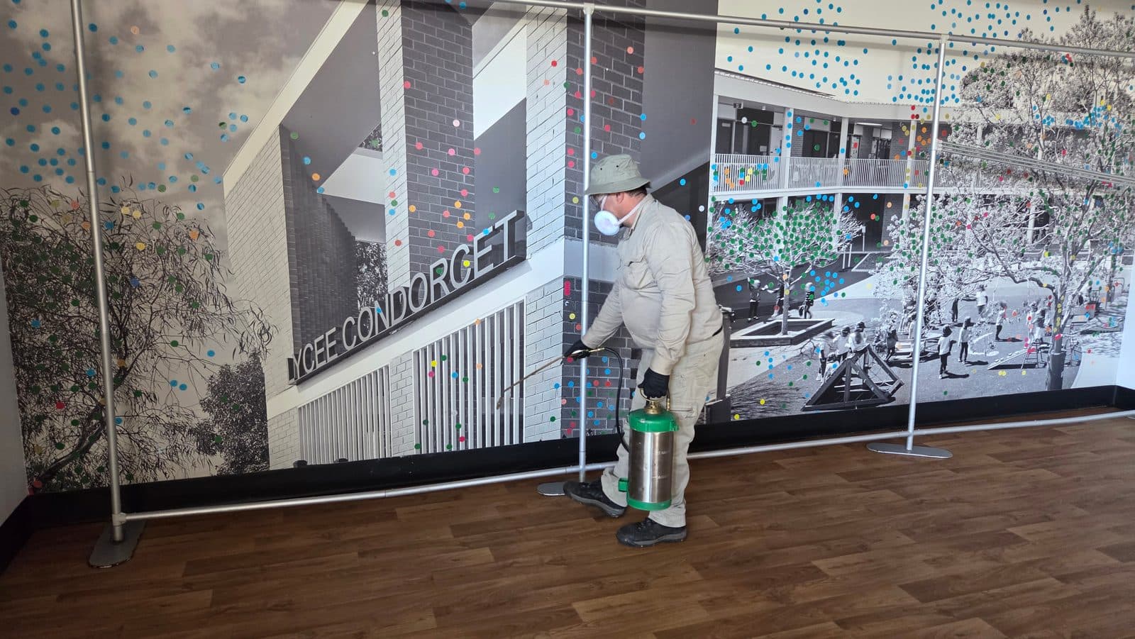 A technician in protective gear spraying around the outside of a building