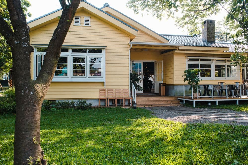 A yellow weatherboard house with a front lawn
